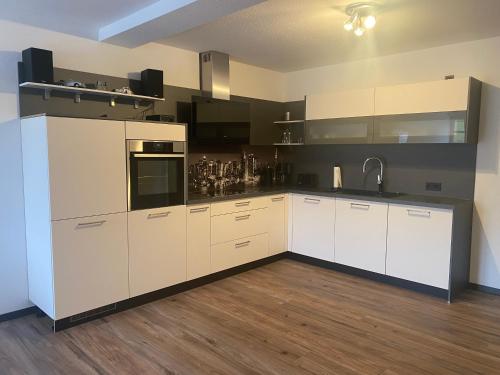 a large kitchen with white cabinets and a wooden floor at Ferienwohnung Haus Waldesruh in Olsberg