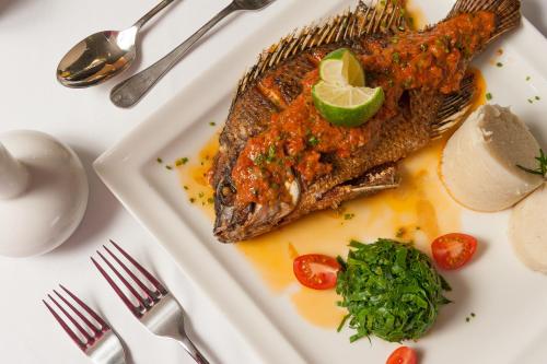 a plate of food with fish on a table at Acacia Premier Hotel in Kisumu