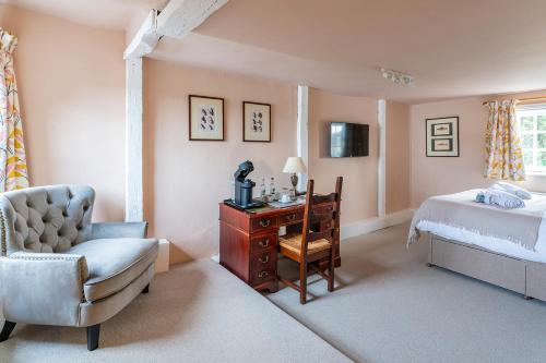 1 dormitorio con cama, silla y escritorio en The White Horse, Rogate en Petersfield