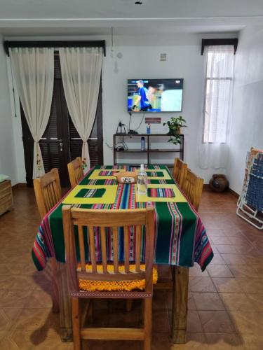 a dining room with a table with chairs and a television at A Lau' De Los Álamos in Humahuaca