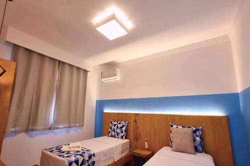 - une chambre avec 2 lits et un mur bleu dans l'établissement Apto térreo 2Q condomínio c/ piscina, churrasqueira e garagem - a apenas 1km da Axé Moi, à Porto Seguro
