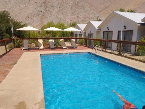 una piscina frente a una casa con montaña en Cabañas Imperio Pisco Elqui, en Pisco Elqui