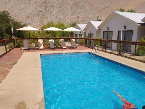 a swimming pool in front of a house with a mountain at Cabañas Imperio Pisco Elqui in Pisco Elqui