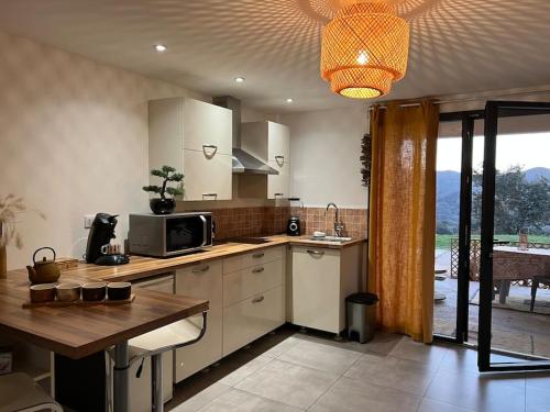 une cuisine avec des armoires blanches et une table avec un micro-ondes dans l'établissement Studio proche Ajaccio, à Ocana