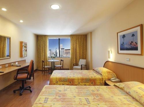 una camera d'albergo con 2 letti e una scrivania di Windsor Guanabara Hotel a Rio de Janeiro