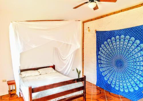 1 dormitorio con 1 cama y una pintura en la pared en Mambo Ecohostal, en San Lorenzo