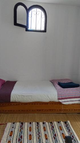a bed in a room with a window and a rug at Dar Gara in Tangier