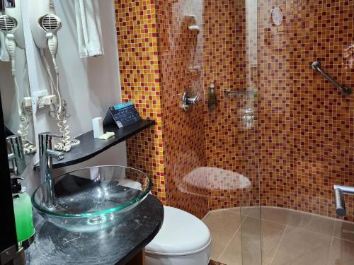 y baño con lavabo de cristal y ducha. en Hotel 5 Elementos Corferias by HBP en Bogotá