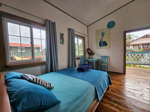 a bedroom with a bed with blue sheets and a window at Casa Pelicano in Bocas Town