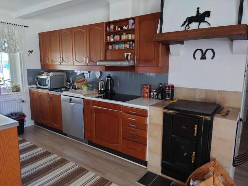 a kitchen with wooden cabinets and a black stove at Lilla Röaby in Bräkne-Hoby