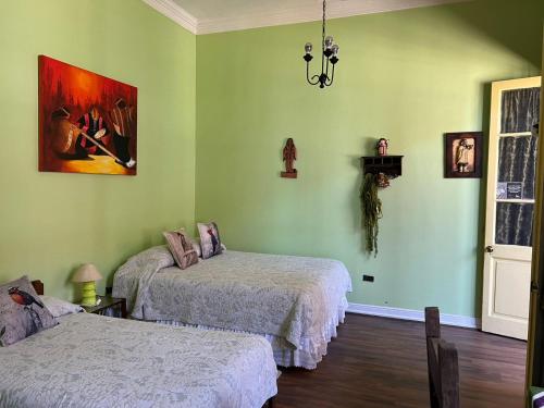 two beds in a room with green walls at El Mirador De Valparaiso in Valparaíso