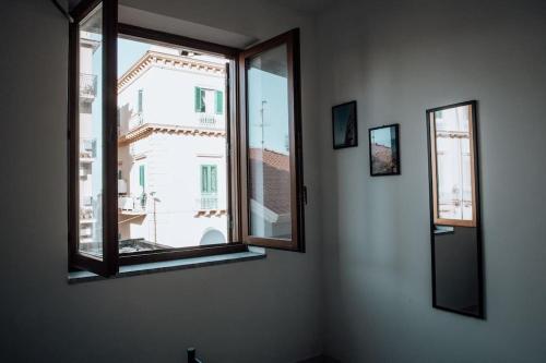 a room with two windows and a view of a building at Three-Square house {apartment} in Gioiosa Marea