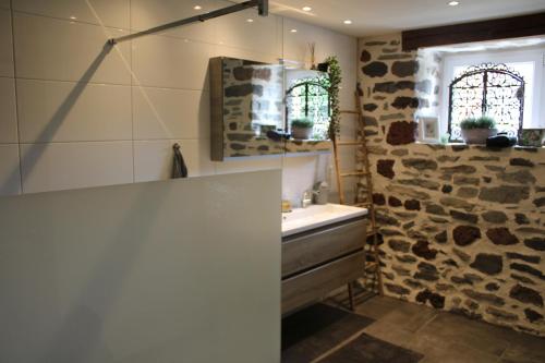 baño con lavabo y pared de piedra en Maison La pierre du lezard, 