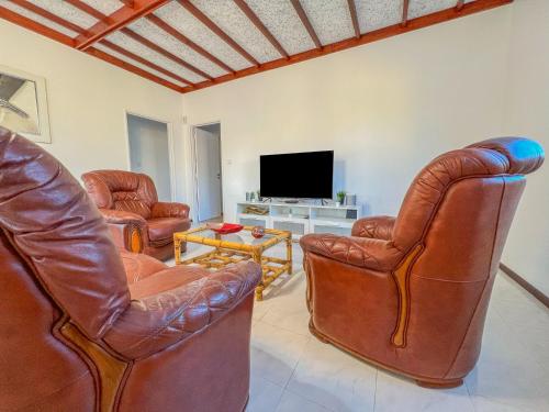 a living room with leather chairs and a television at Maison Familiale - Torreira in Torreira