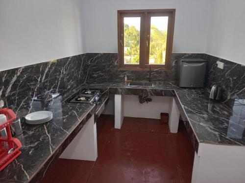 a kitchen with a counter with a sink and a window at VILLA AAA WELIGAMA in Weligama