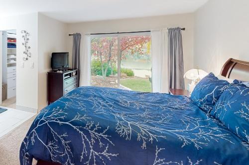 a bedroom with a bed with a blue comforter and a window at Lake Cortez Cottage 