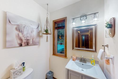 a bathroom with a sink and a toilet with a picture of a cow at The Pony Creek Forest Retreat in North Bend