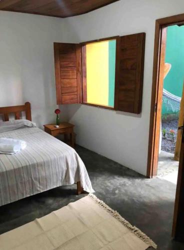 um quarto com uma cama e uma janela em Chalé Casa Vitoria - Quarto Inferior em Trancoso
