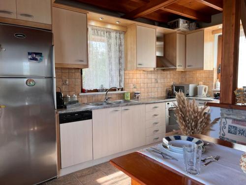 a kitchen with white cabinets and a stainless steel refrigerator at VS Villa Killini in Káto Panayía