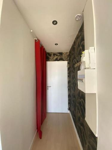 un couloir avec une porte blanche et des rideaux rouges dans l'établissement Appartement face mer (vue 180°) avec balcon, à Saint-Jean-de-Monts