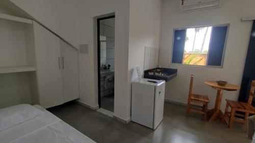 um quarto com um frigorífico, uma mesa e uma janela em Pousada Flor do Campo Cipó em Santana do Riacho