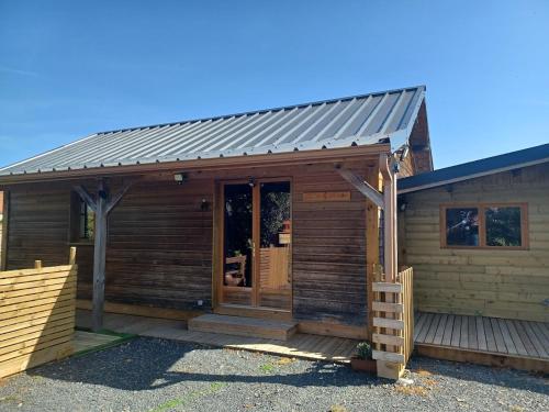 a wooden cabin with a metal roof at CHALETS POUR FAMILLE ET AMIS in La Chapelle-aux-Chasses