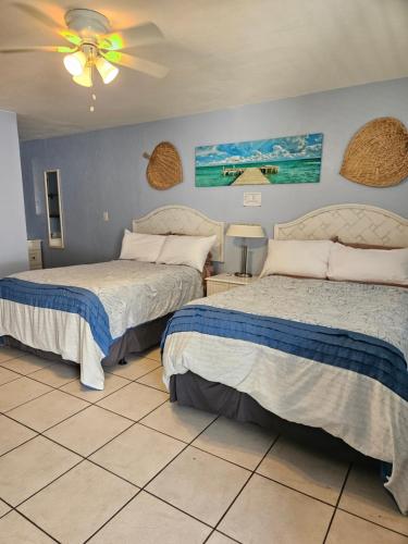 a bedroom with two beds and a ceiling fan at Oasis Palms Resort in St Pete Beach