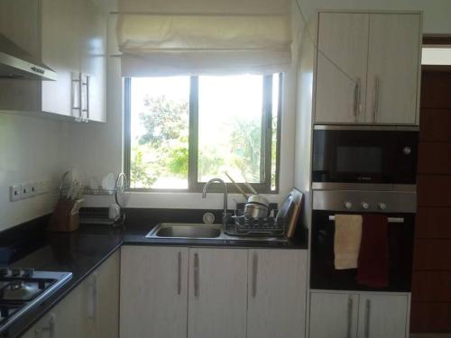 a kitchen with a sink and a microwave and a window at Entire residential swahili home-Vipingo in Kikambala
