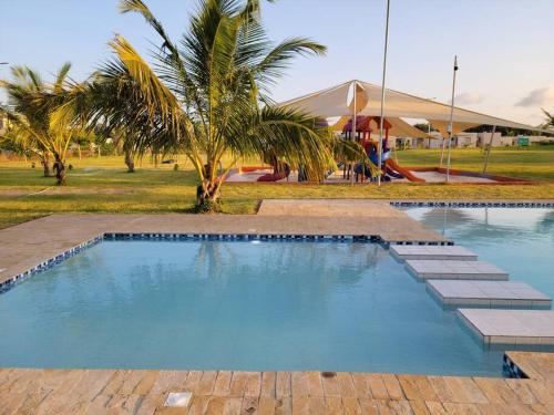 a swimming pool with a palm tree and a playground at Entire residential swahili home-Vipingo in Kikambala