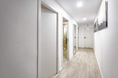 un pasillo con paredes blancas y un espejo grande en Apartamentos Hortaleza, en Madrid