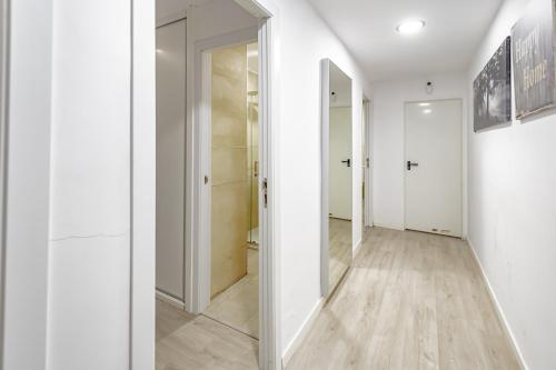 un pasillo con paredes blancas y un espejo grande en Apartamentos Hortaleza, en Madrid