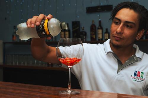 a man pouring wine into a wine glass at Hotel El Cocobolo Food&Rest Room 3 B&B WiFi AC Pkg Free Swimmingpool in Liberia