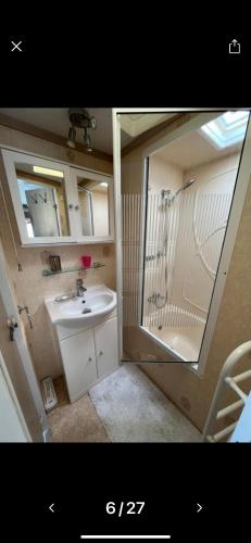 uma casa de banho com um lavatório, um chuveiro e um espelho. em Rogers Retreat em Scratby