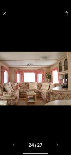 uma sala de estar com um sofá grande e cortinas vermelhas em Rogers Retreat em Scratby