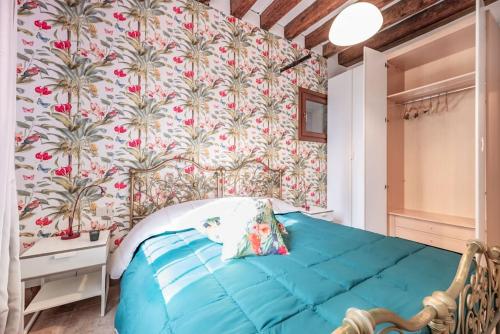 a bedroom with a blue bed with a floral wallpaper at Guggenheim House [ Dorsoduro ] in Venice