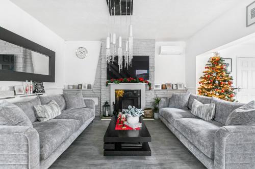 a living room with a couch and a christmas tree at Hampton Oasis with Heated Pool & Large Garden in Molesey