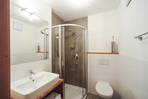 een badkamer met een douche, een wastafel en een toilet bij Almrausch Apartments in Sesto