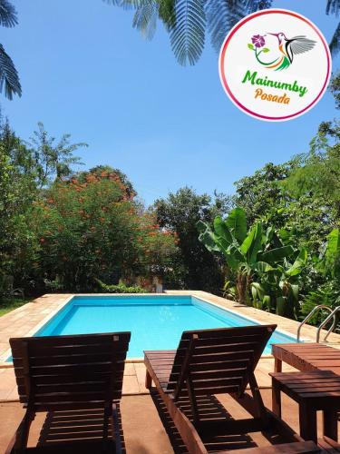 a swimming pool with two chairs and a sign at Mainumby- Colibri Posada in Puerto Iguazú
