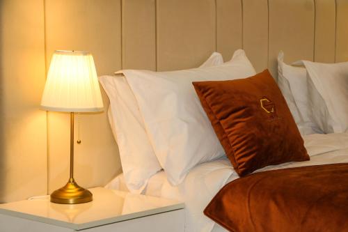 Cama con almohadas blancas y mesa con lámpara en Hotel Golden Sunset Dakhla, en Dakhla