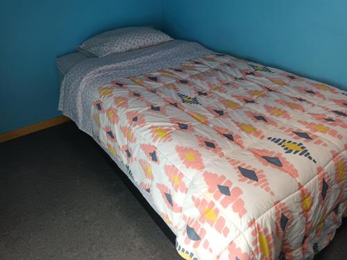 a bed in a bedroom with a blue wall at Cabaña Dallana in Valdivia