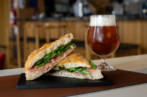 a sandwich cut in half next to a glass of beer at Hampton By Hilton Bariloche in San Carlos de Bariloche