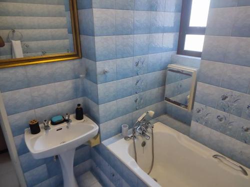 ein blau gefliestes Badezimmer mit einem Waschbecken und einer Badewanne in der Unterkunft Serenity Seascapes in Amanzimtoti