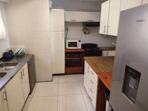 a small kitchen with white cabinets and a microwave at Serenity Seascapes in Amanzimtoti