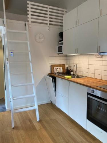 una cocina con armarios blancos y una escalera en Tiny grey house with loft, 15 min from city center, en Gotemburgo
