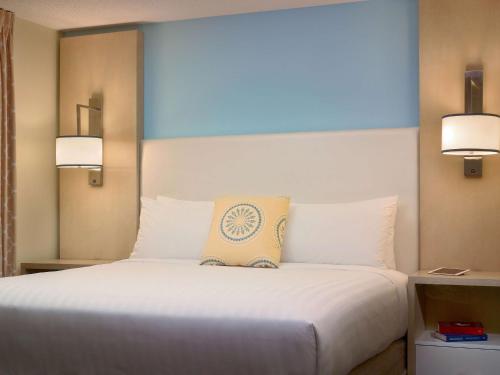 Staybridge Suites Burlington - Boston, an IHG Hotel في برلنغتون: غرفة نوم بسرير ابيض كبير بها مصباحين