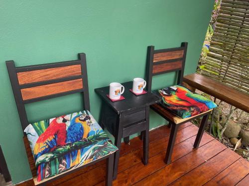 a room with two chairs and a table and a table with a parrot on at Casitas Del Rio Riverfront Nature Lodge in Uvita