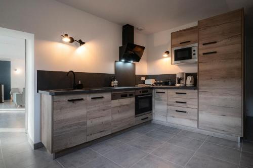 - une cuisine avec des placards en bois et un four micro-ondes dans l'établissement Gîte Sous le Verger, à Songeson