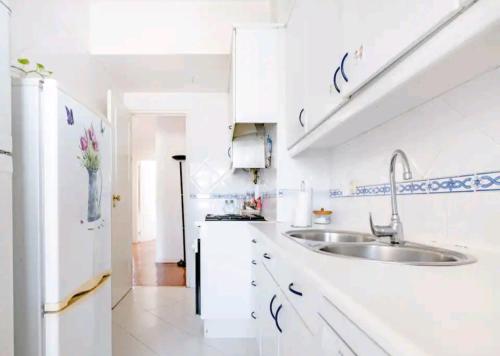 een witte keuken met een wastafel en een koelkast bij Rigoli Room in Lissabon