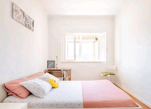 een witte slaapkamer met een bed en een raam bij Rigoli Room in Lissabon
