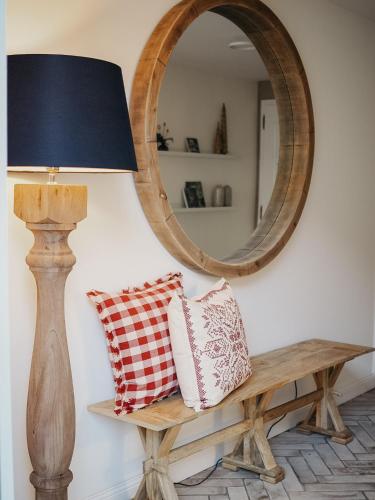 a mirror and a bench with pillows and a lamp at Roudenhaff Guestfarm in Echternach